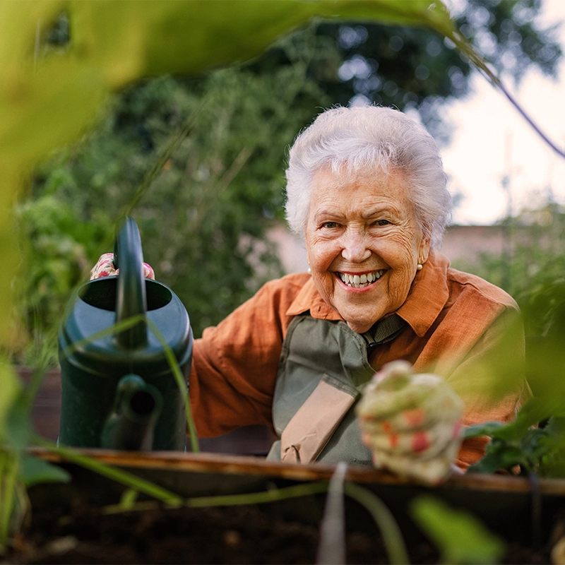 Ältere Dame gießt Blumen